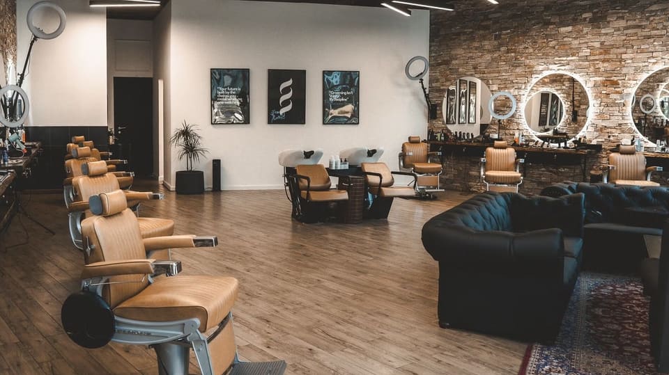 The floor at Casa Barbershop: tan leather chairs, stone wall and Chesterfield sofas