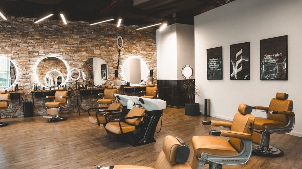 Stone wall with lit round mirrors and barber chairs at Casa
