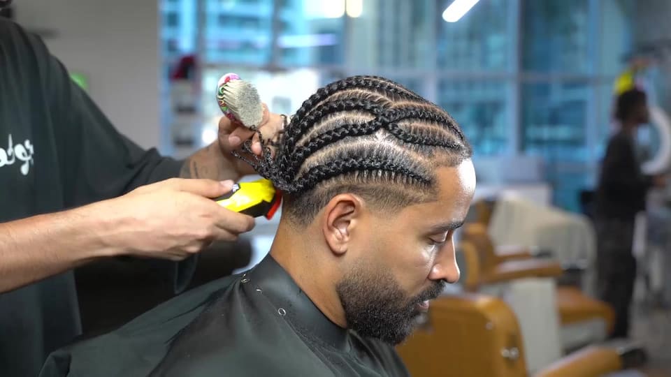 Cornrow braids being finished with a trimmer at Casa